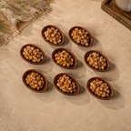Seven Ceramic Amber Tide Petite Server filled with a chickpea salad, arranged on a beige stone surface with a rustic cloth and tray in the background.
