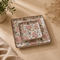 OZAY Living Peony serving platter set with a pink and blue floral pattern on a beige background, styled on a beige fabric surface with dried flowers and a potted plant.