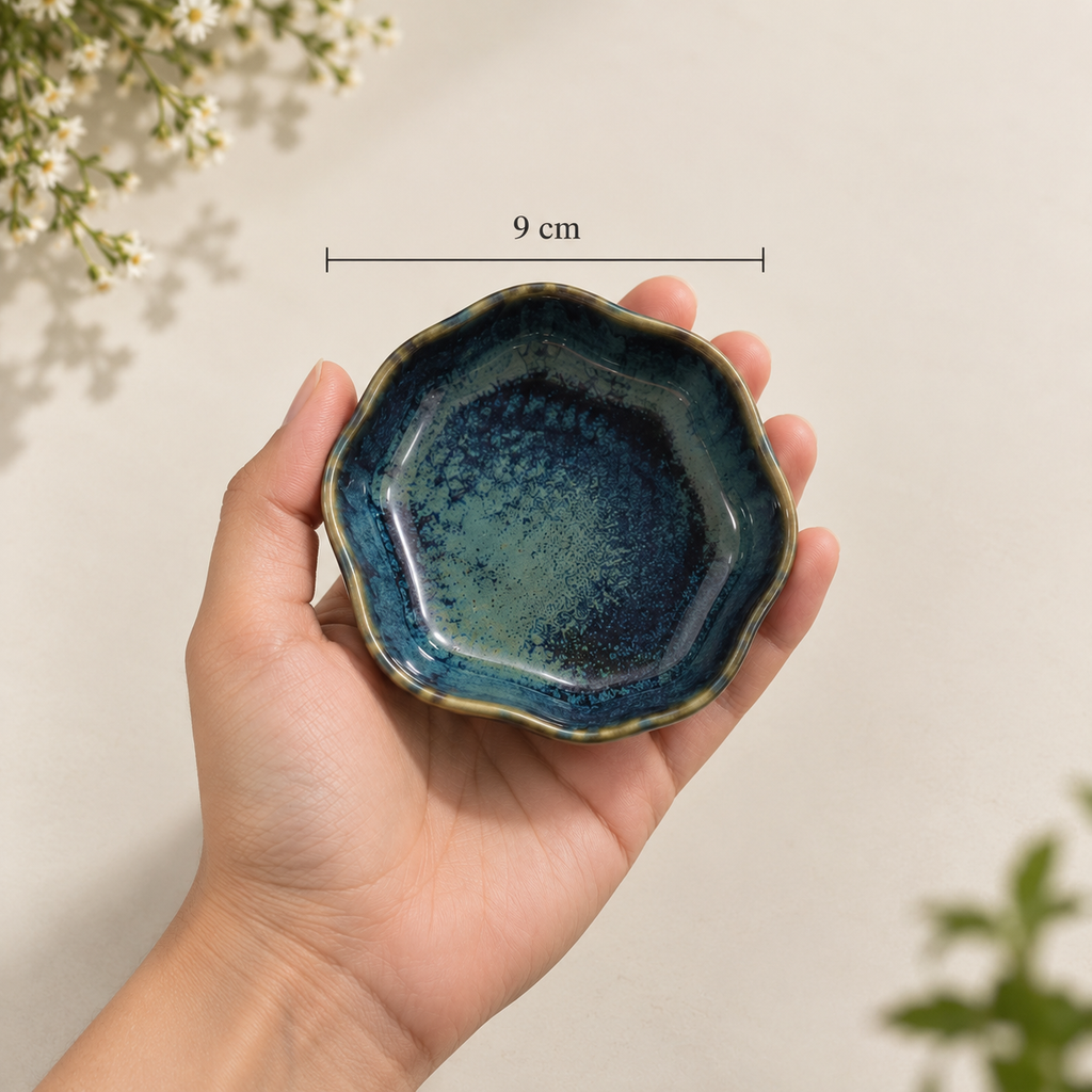 A hand holds Willow Petite Servers ceramic serving dish with a blue and green glaze and a gold-toned rim. A measurement overlay indicates the dish is 9 cm in diameter.